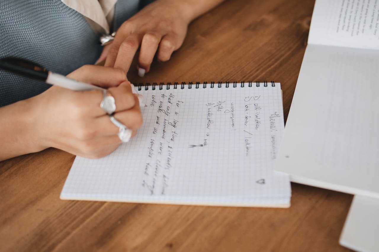 Close-up of hands writing on a notepad, emphasizing learning and education